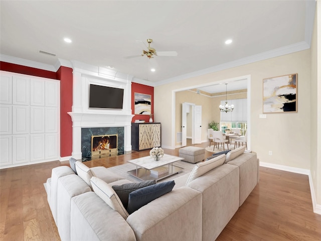 living area featuring visible vents, ornamental molding, a high end fireplace, wood finished floors, and baseboards