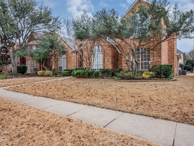 traditional-style home featuring brick siding and a front lawn