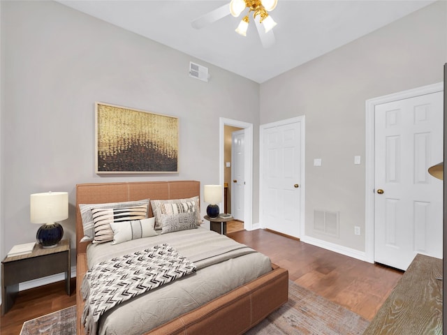 bedroom featuring a ceiling fan, wood finished floors, visible vents, and baseboards