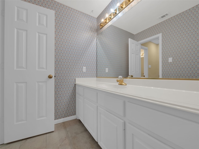 bathroom with visible vents, vanity, tile patterned flooring, baseboards, and wallpapered walls