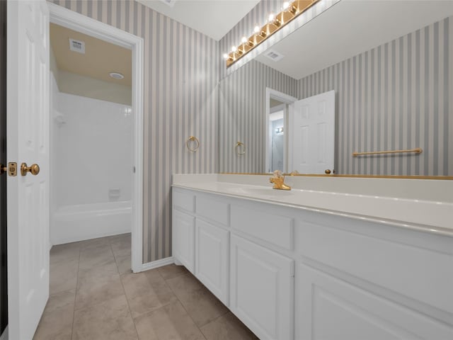 bathroom with shower / bathtub combination, visible vents, vanity, baseboards, and wallpapered walls