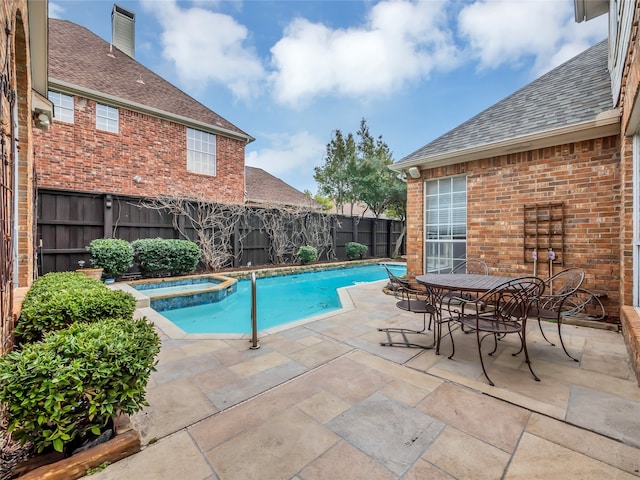 view of swimming pool with a pool with connected hot tub, a fenced backyard, a patio, and outdoor dining area