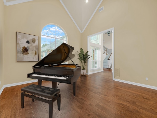 sitting room with high vaulted ceiling, wood finished floors, and visible vents