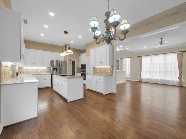 kitchen with dark wood-style floors, a kitchen island, stovetop, white cabinetry, and backsplash