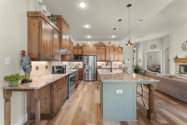 kitchen with under cabinet range hood, a breakfast bar, a sink, visible vents, and appliances with stainless steel finishes