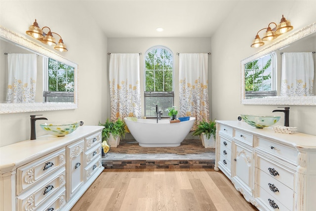 bathroom featuring plenty of natural light, vanity, a freestanding bath, and wood finished floors