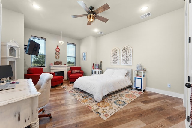 bedroom with recessed lighting, visible vents, a fireplace, and wood finished floors