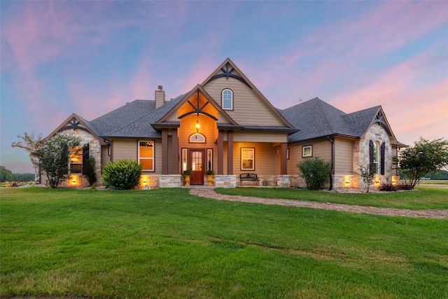 craftsman inspired home featuring a shingled roof, stone siding, a chimney, and a front lawn