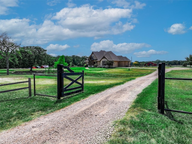 view of gate featuring a yard, a rural view, and fence