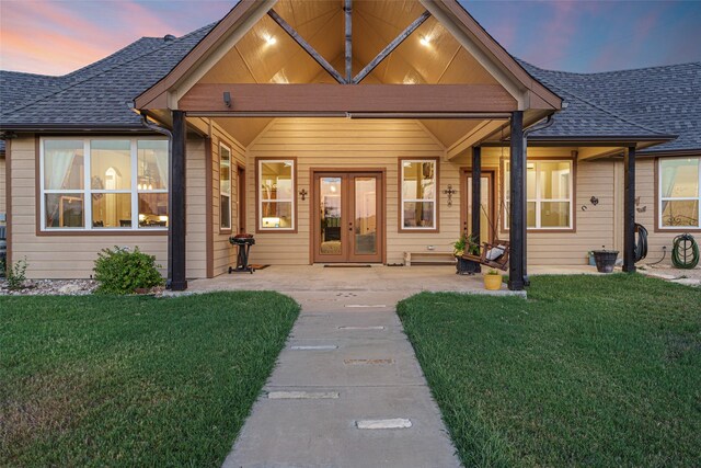 view of front of property featuring french doors, roof with shingles, and a front lawn