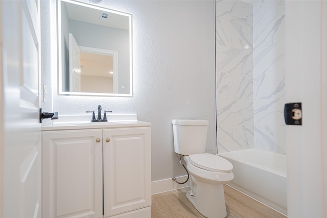 full bathroom featuring a textured wall, vanity, toilet, and wood finished floors