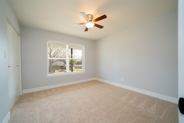 carpeted spare room featuring ceiling fan and baseboards