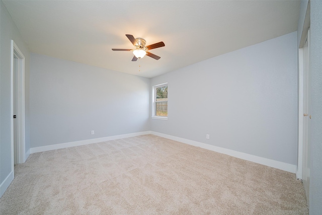 spare room with baseboards, ceiling fan, and light colored carpet