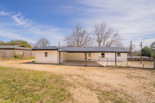 back of house featuring a patio area, metal roof, and a fenced backyard