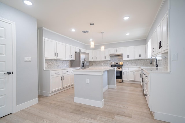 kitchen featuring visible vents, a center island, stainless steel appliances, under cabinet range hood, and a sink