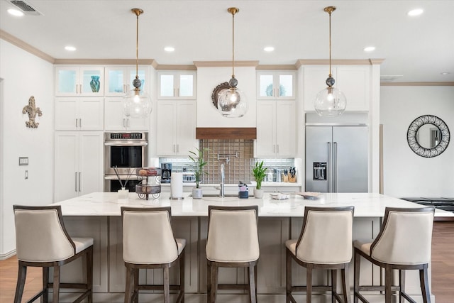 kitchen with a large island, crown molding, stainless steel appliances, and wood finished floors