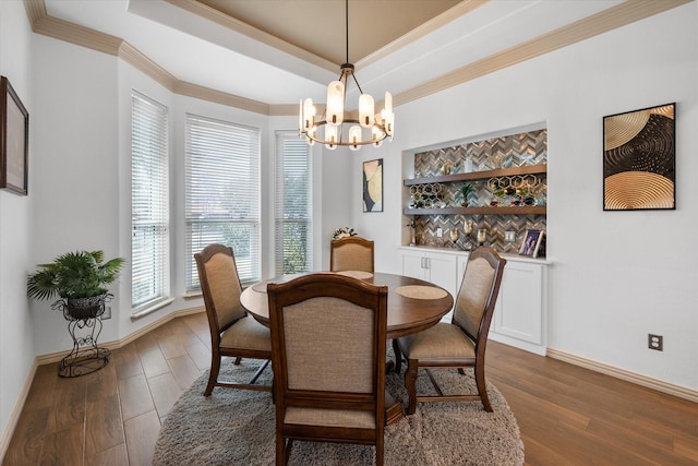 dining space featuring a tray ceiling, a chandelier, wood finished floors, and ornamental molding