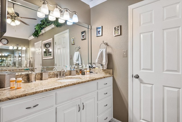 bathroom featuring crown molding, a textured wall, ceiling fan, and vanity