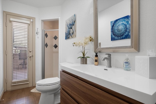 full bathroom with toilet, a stall shower, wood finished floors, and vanity