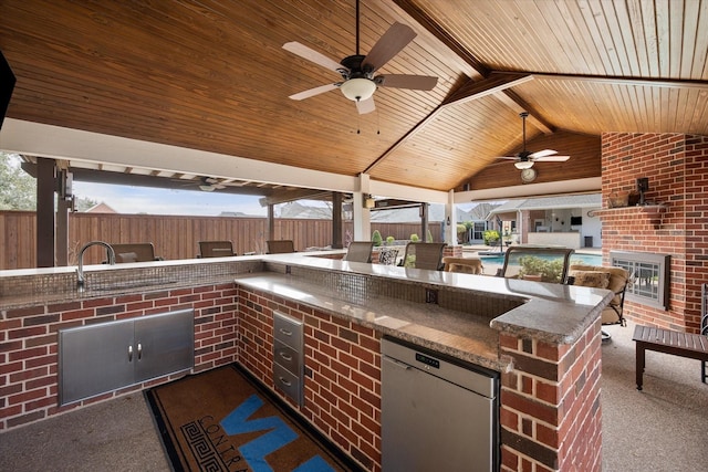 view of patio with an outdoor kitchen, a fenced backyard, outdoor wet bar, and a ceiling fan