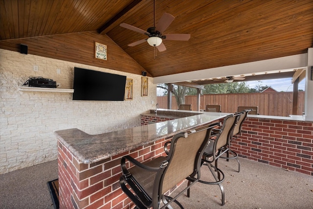 view of patio / terrace featuring outdoor wet bar, fence, exterior kitchen, and ceiling fan