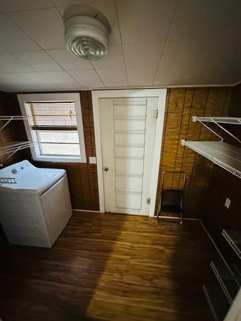 laundry room featuring washer / dryer, laundry area, dark wood-type flooring, and wood walls