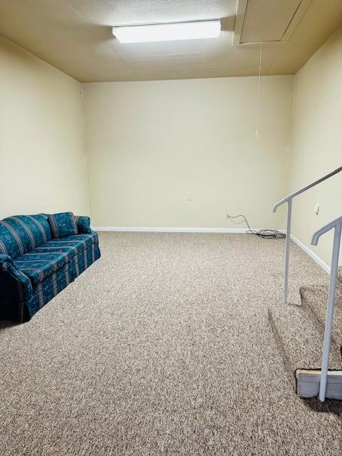 interior space featuring carpet, attic access, baseboards, and a textured ceiling