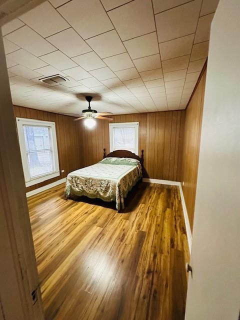 bedroom featuring multiple windows, wood finished floors, visible vents, and baseboards