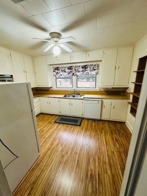 kitchen with a healthy amount of sunlight, white cabinets, a sink, wood finished floors, and white appliances