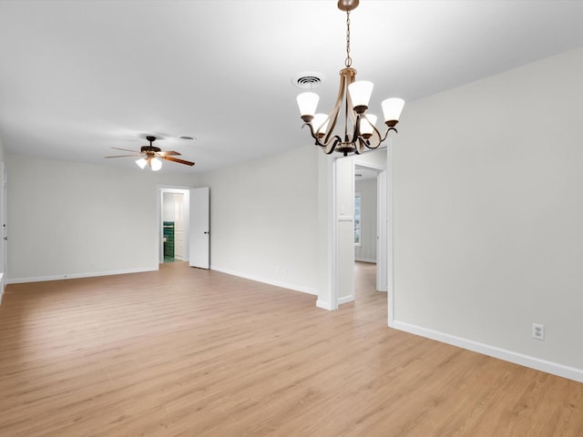 empty room featuring light wood-type flooring, visible vents, baseboards, and ceiling fan with notable chandelier