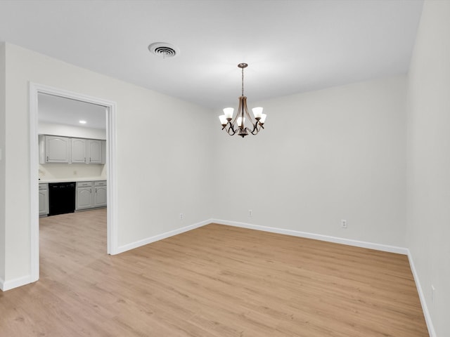 spare room with a notable chandelier, light wood-style flooring, visible vents, and baseboards