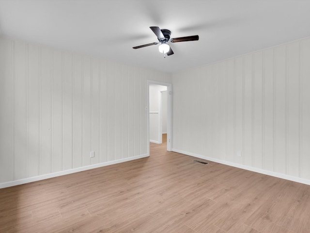 spare room featuring light wood-style floors, baseboards, visible vents, and a ceiling fan