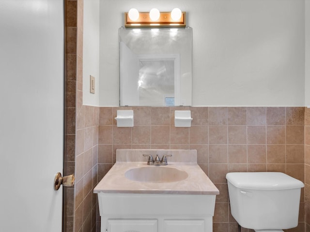 bathroom with toilet, tile walls, and vanity