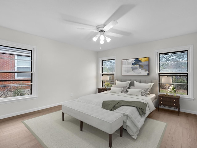 bedroom featuring ceiling fan, light wood-style flooring, and baseboards