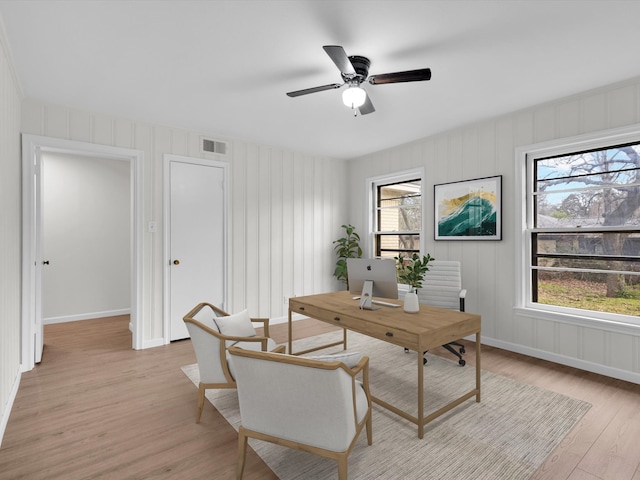 home office featuring light wood-style floors, ceiling fan, visible vents, and a wealth of natural light