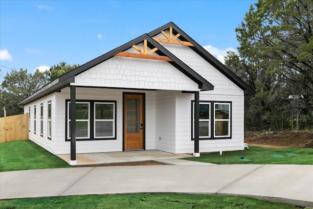 modern inspired farmhouse featuring a porch, a front yard, and fence