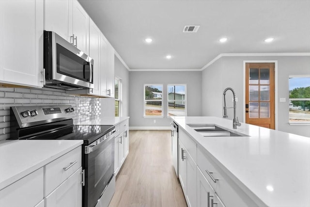 kitchen featuring crown molding, stainless steel appliances, visible vents, backsplash, and a sink