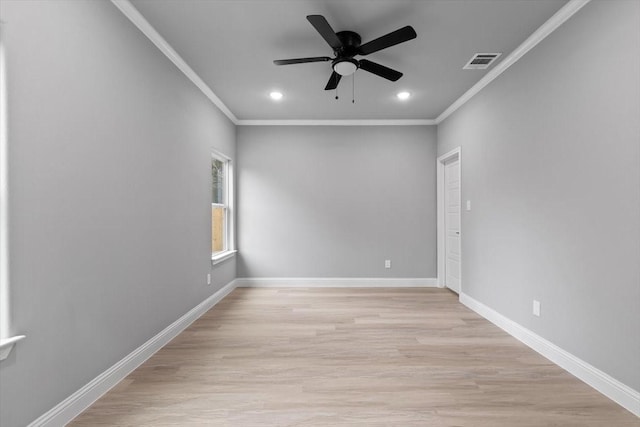 empty room with light wood-style floors, visible vents, crown molding, and baseboards