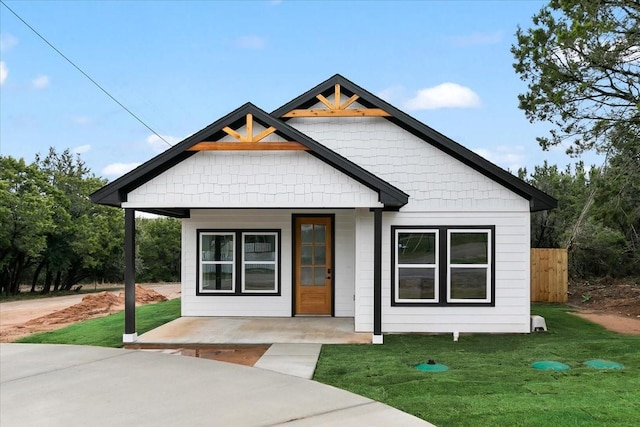 modern farmhouse featuring covered porch, fence, and a front lawn