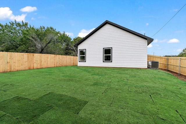 view of side of home featuring central AC, a yard, and a fenced backyard