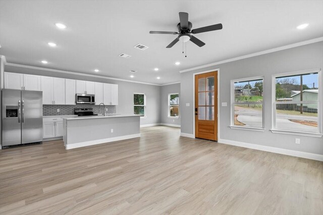 kitchen with stainless steel appliances, tasteful backsplash, light countertops, visible vents, and open floor plan