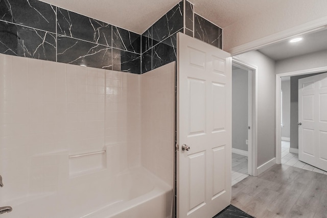 full bathroom featuring  shower combination, baseboards, and wood finished floors