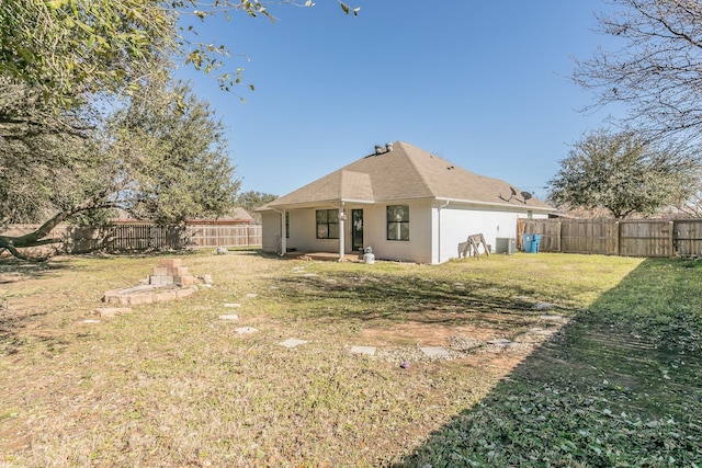 rear view of property with stucco siding, a shingled roof, central air condition unit, a lawn, and a fenced backyard