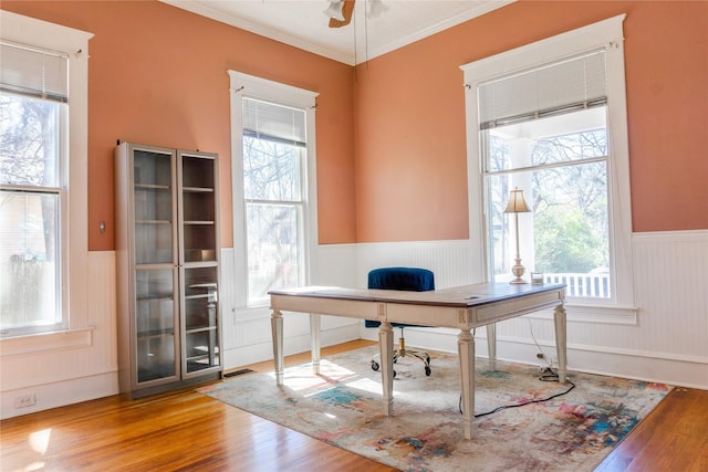 office featuring ceiling fan, a wainscoted wall, wood finished floors, and ornamental molding