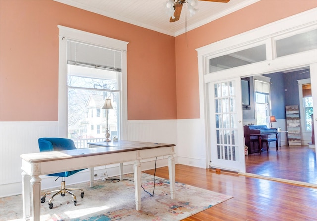 office area with a ceiling fan, wood finished floors, wainscoting, and ornamental molding