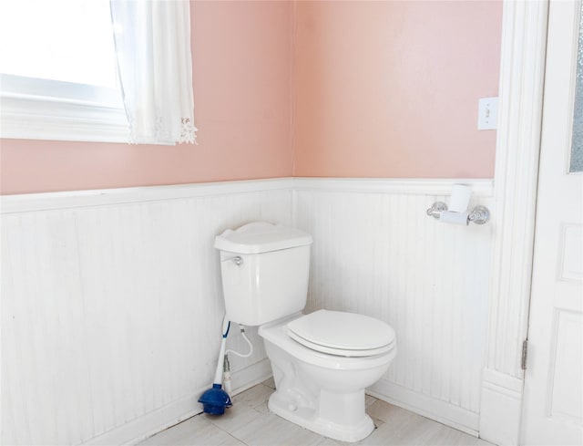 half bath with a wainscoted wall and toilet