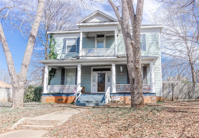 view of front facade with a porch, a balcony, and fence