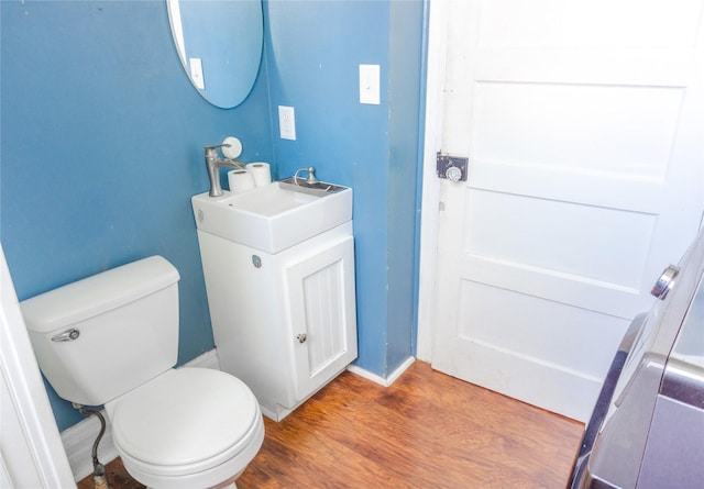 bathroom featuring vanity, toilet, wood finished floors, and baseboards