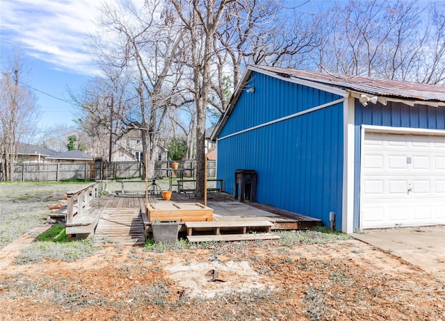 exterior space with an outdoor structure, fence, a garage, and a wooden deck