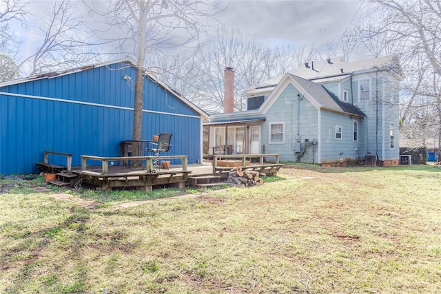 back of house with a wooden deck, a lawn, cooling unit, and a chimney